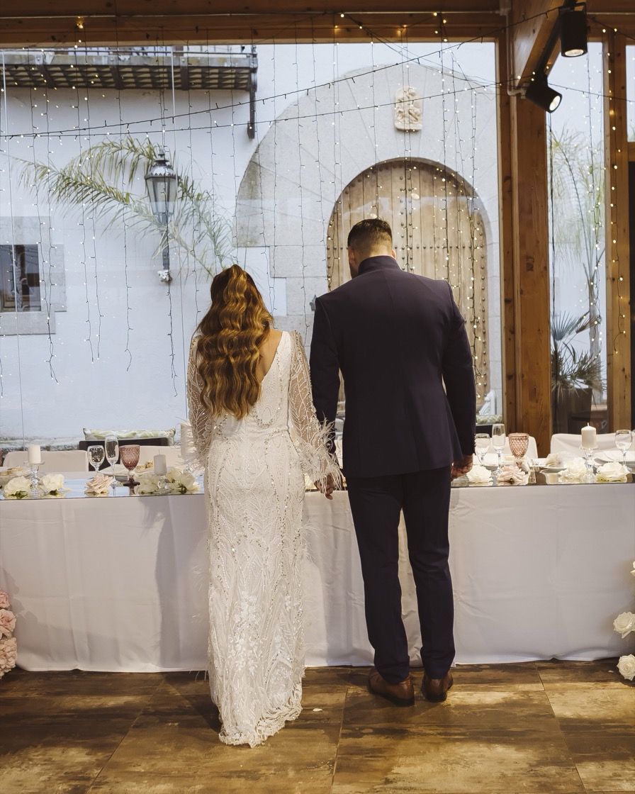 Pareja de espaldas cogida de la mano frente a la mesa nupcial decorada